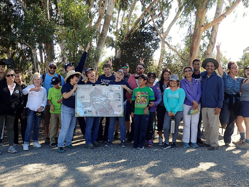 Group of volunteers at Stanley Reach cleanup holding a map of the Alameda Creek Watershed.