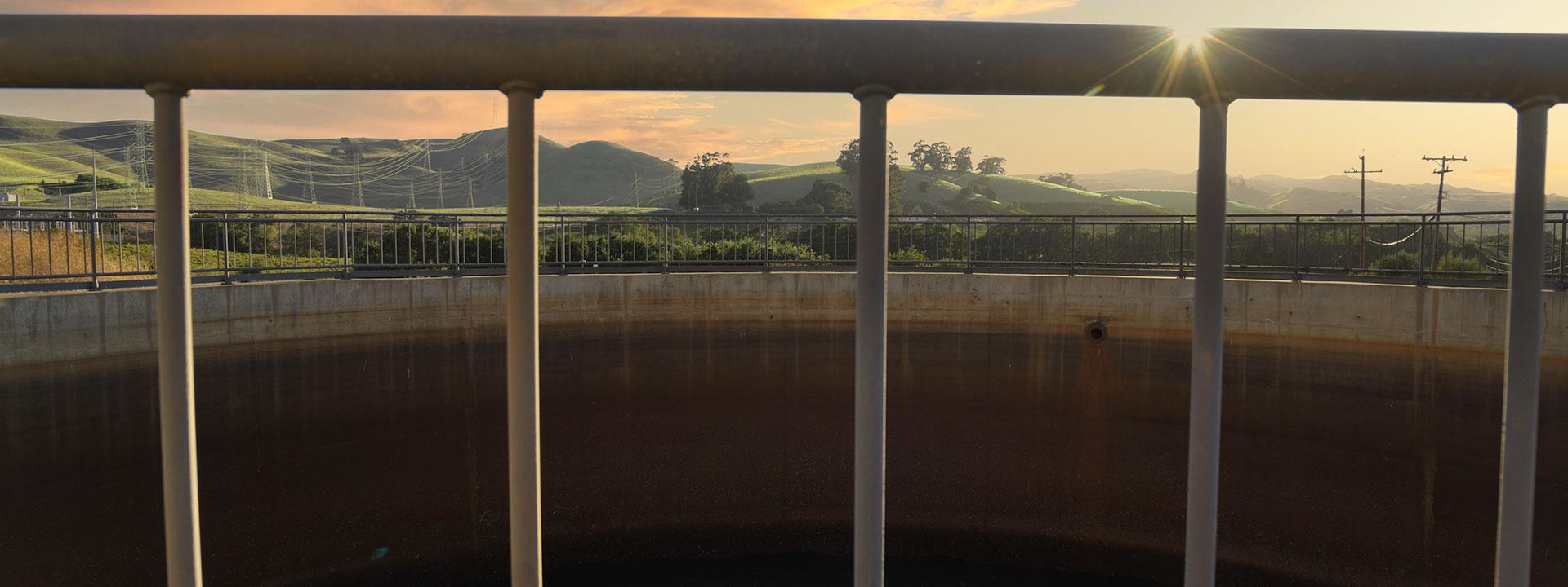 View of a sunset in a green valley through metal railing