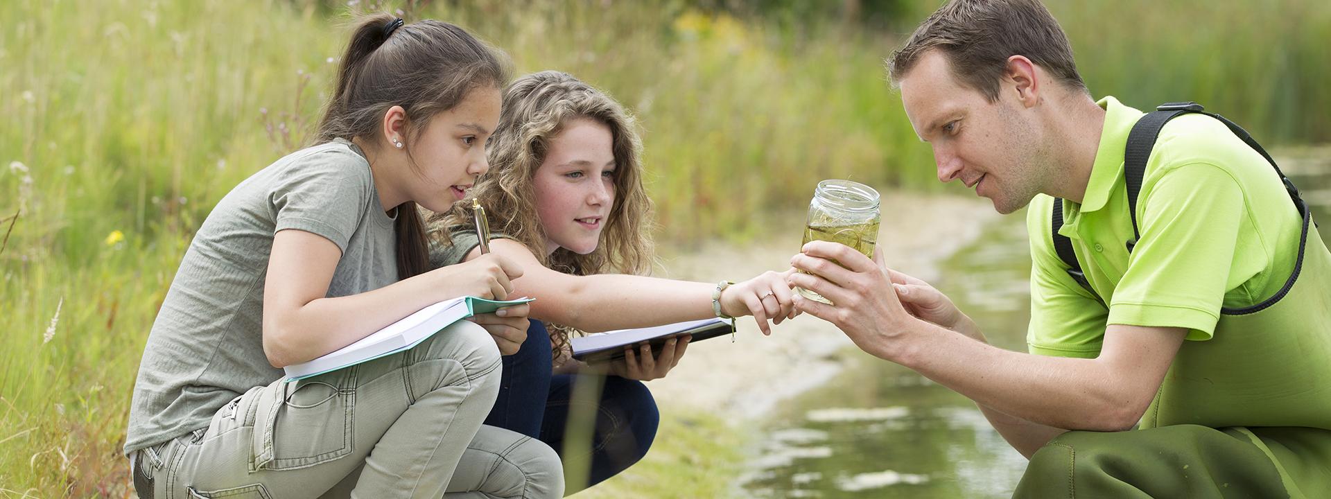 Three people engaged in an outdoor watershed activity, observing water quality