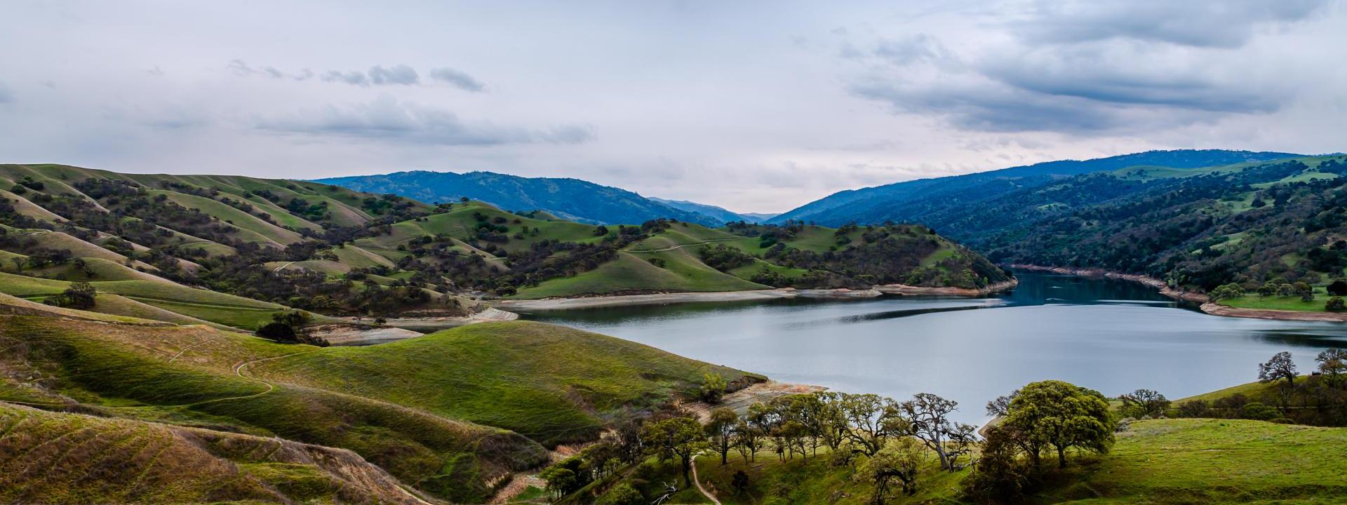 Del Valle Lake surrounded by green hills and gray sky