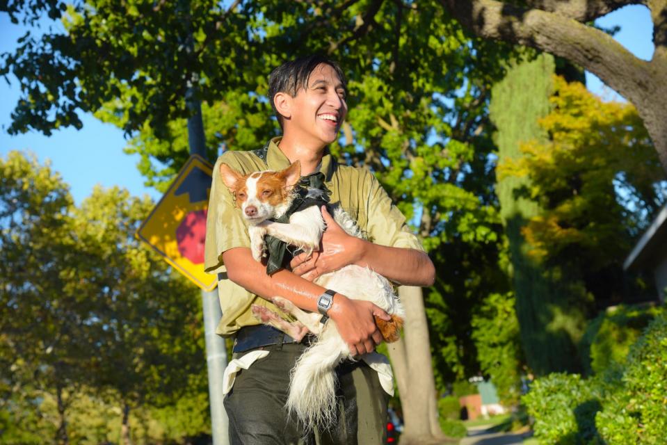 Flood Ready Freddy smiling and holding medium sized white and brown dog in his arms
