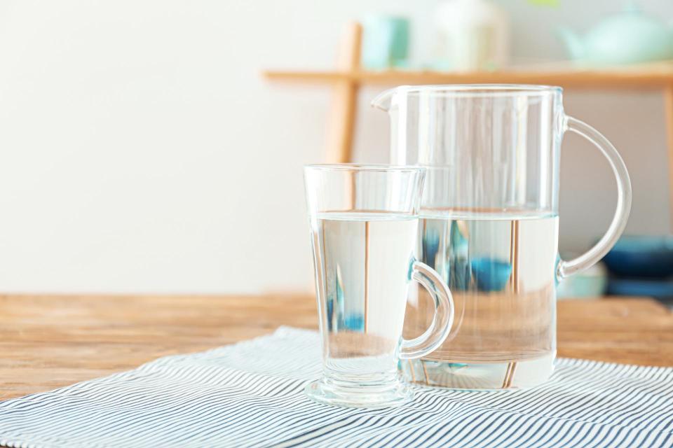A clear pitcher and cup filled with water placed on a table