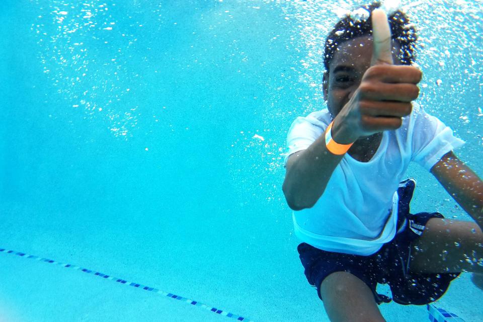 Kid giving a thumbs up while swimming