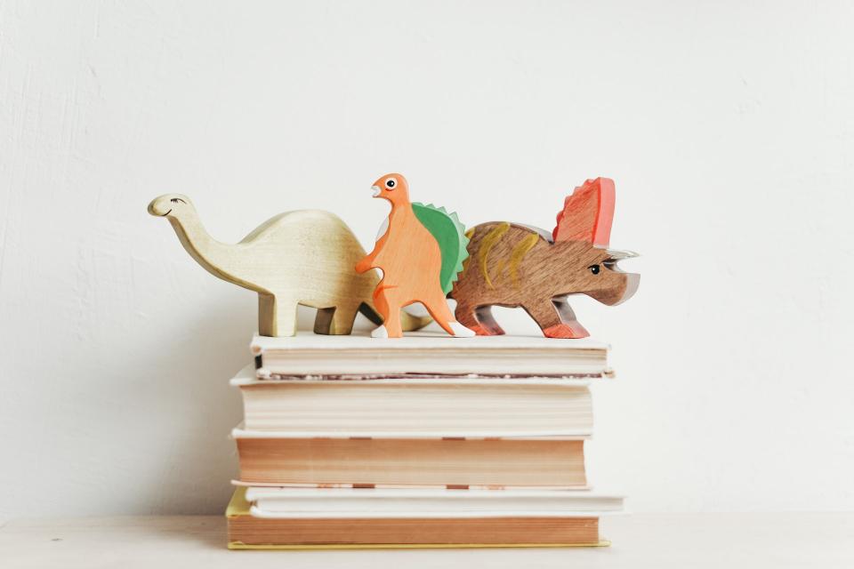 A stack of books with dinosaurs toys sitting on top