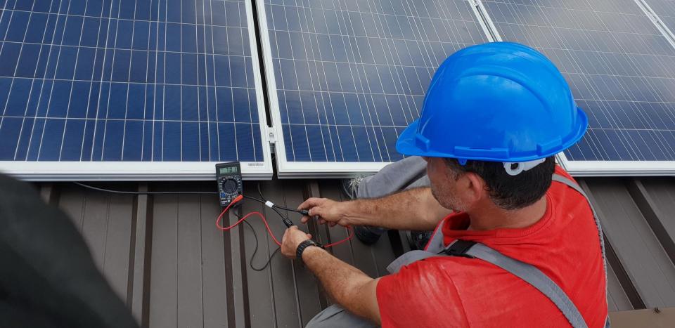 A solar panel engineer testing a solar panel with a voltage meter.
