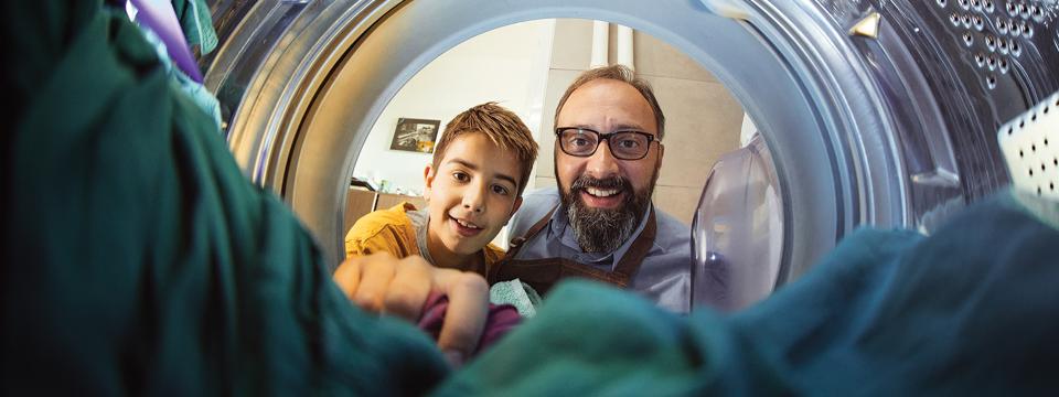 View from inside of a drying machine of a boy and a man looking in