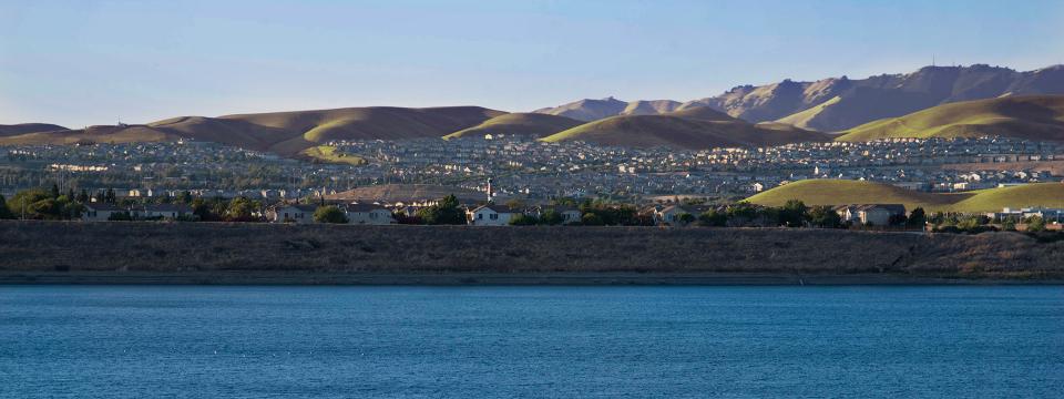 A deep blue body of water with a level city in the distance
