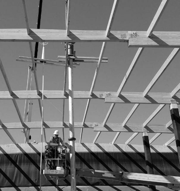 Black and white photo of maintenance employee climbing ladder to exposed beams