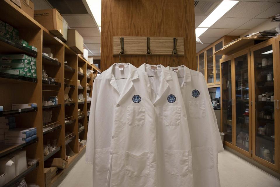 Three lab coats hanging in a locker room
