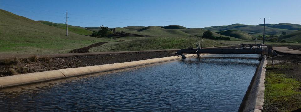 Close up of South Bay Aqueduct will green hills in the background