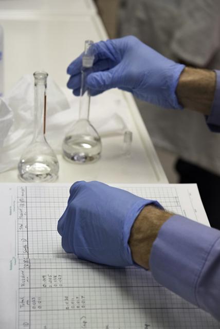 Close up of hands wearing blue gloves holding tubes of water.