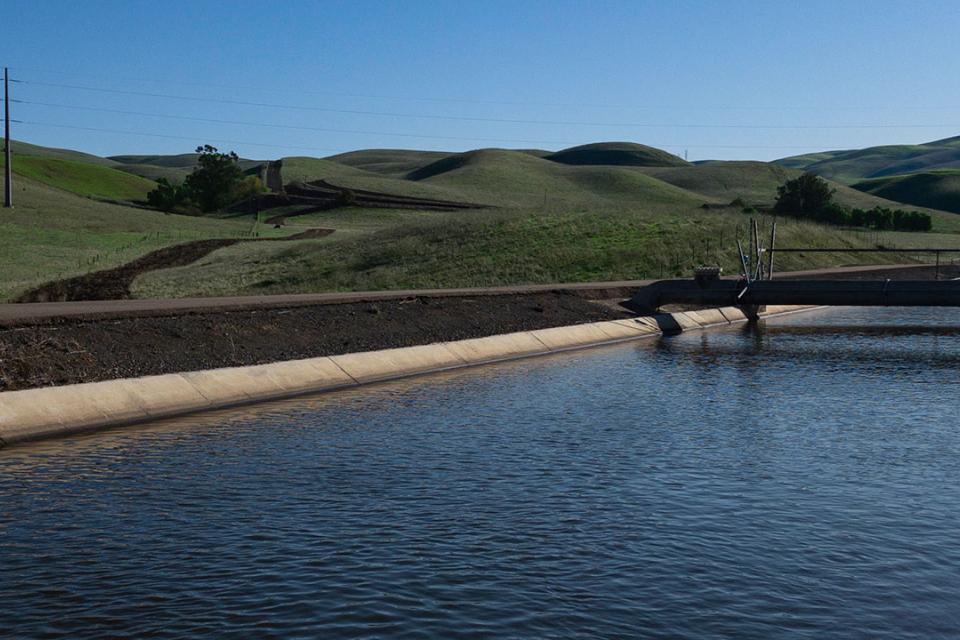 Close up of South Bay Aqueduct will green hills in the background