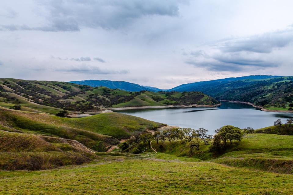 Del Valle Lake surrounded by green hills and gray sky