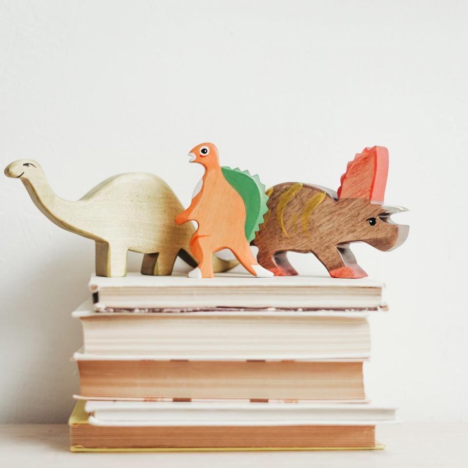 A stack of books with dinosaurs toys sitting on top