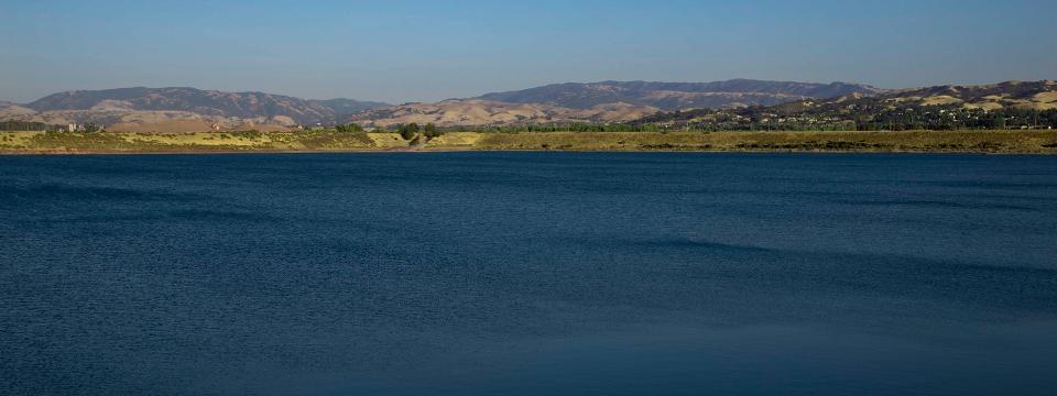 Deep blue body of water with mountain ridge in the background.